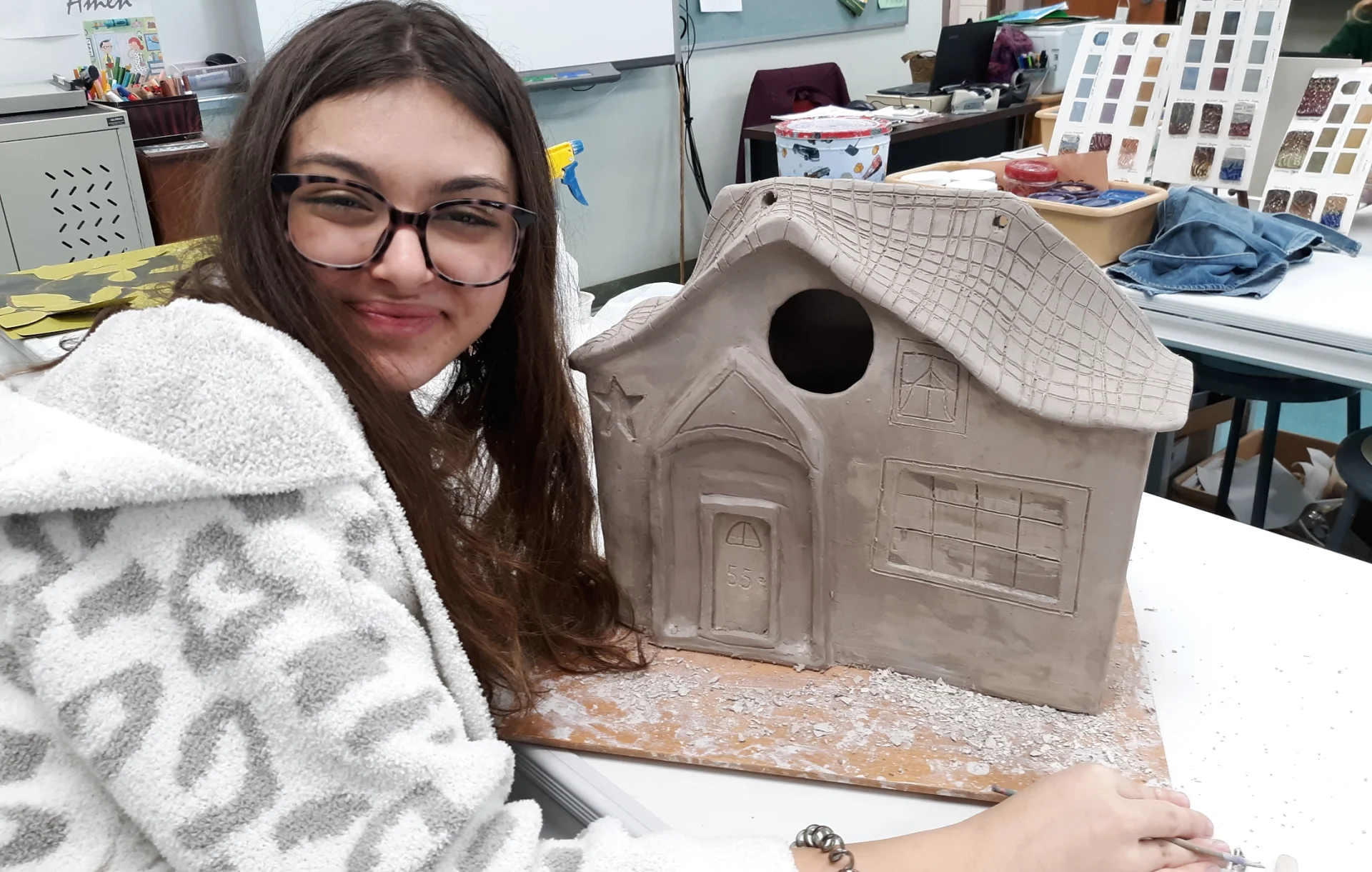 student posing with ceramic house