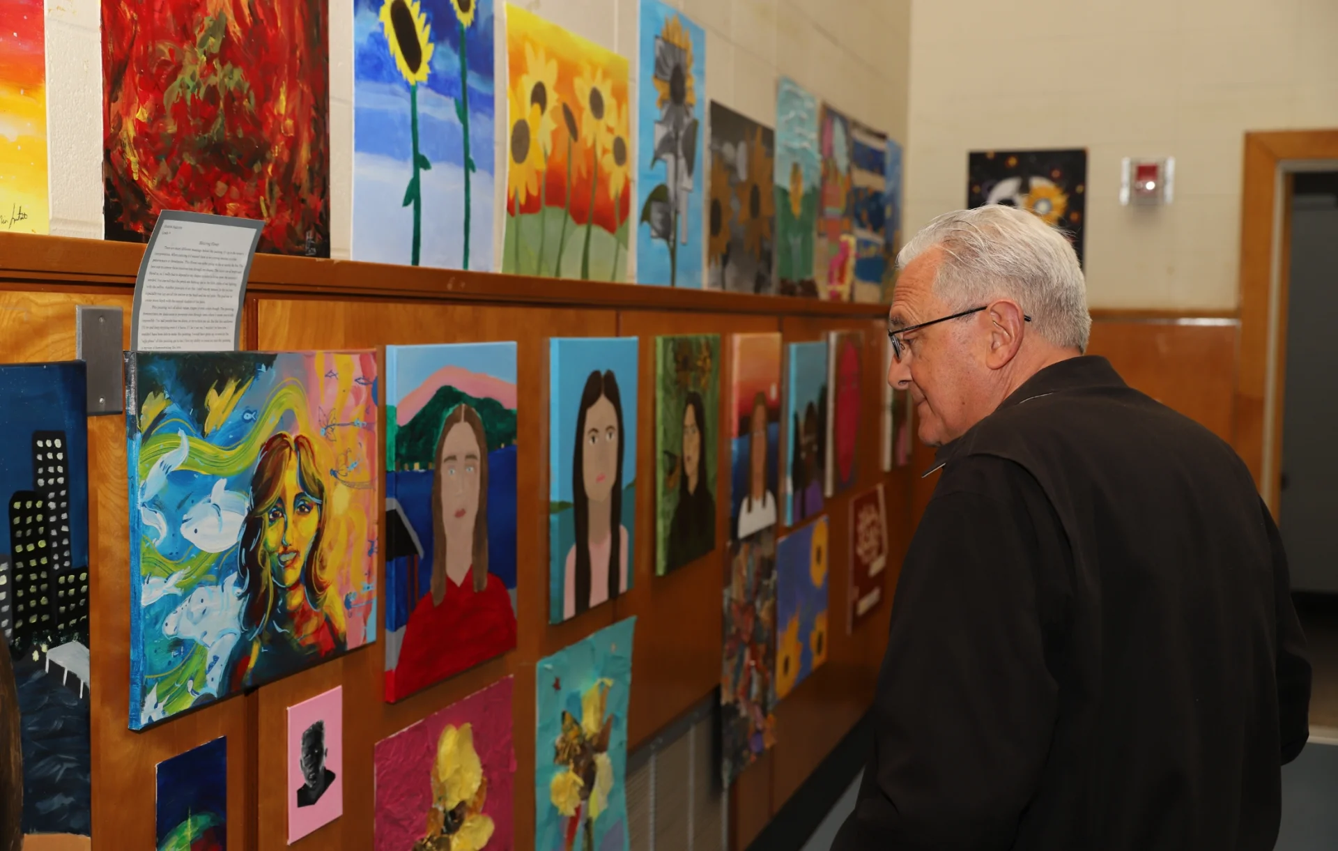 man looking at student art gallery