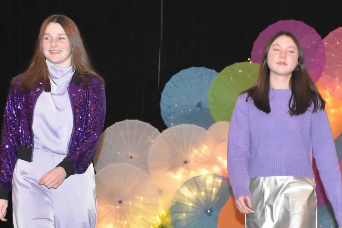 two students in purple walking down the runway