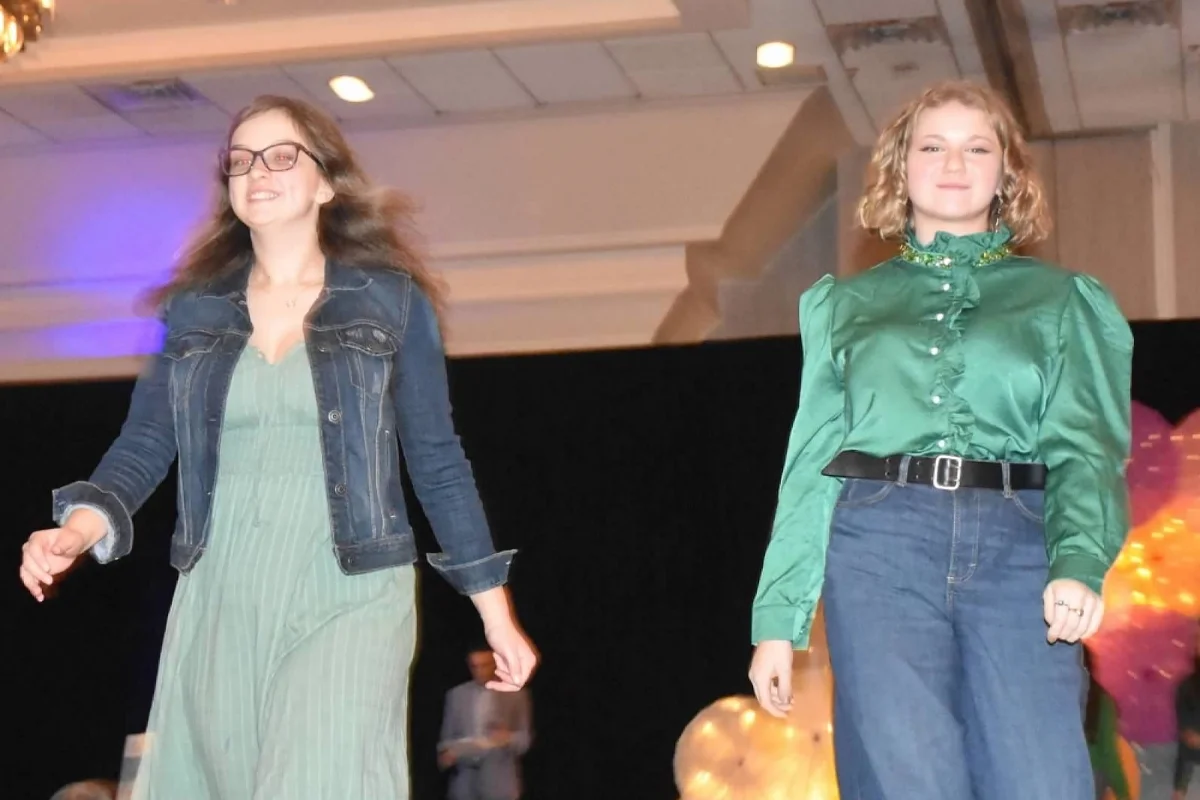 two students in green walking down the runway