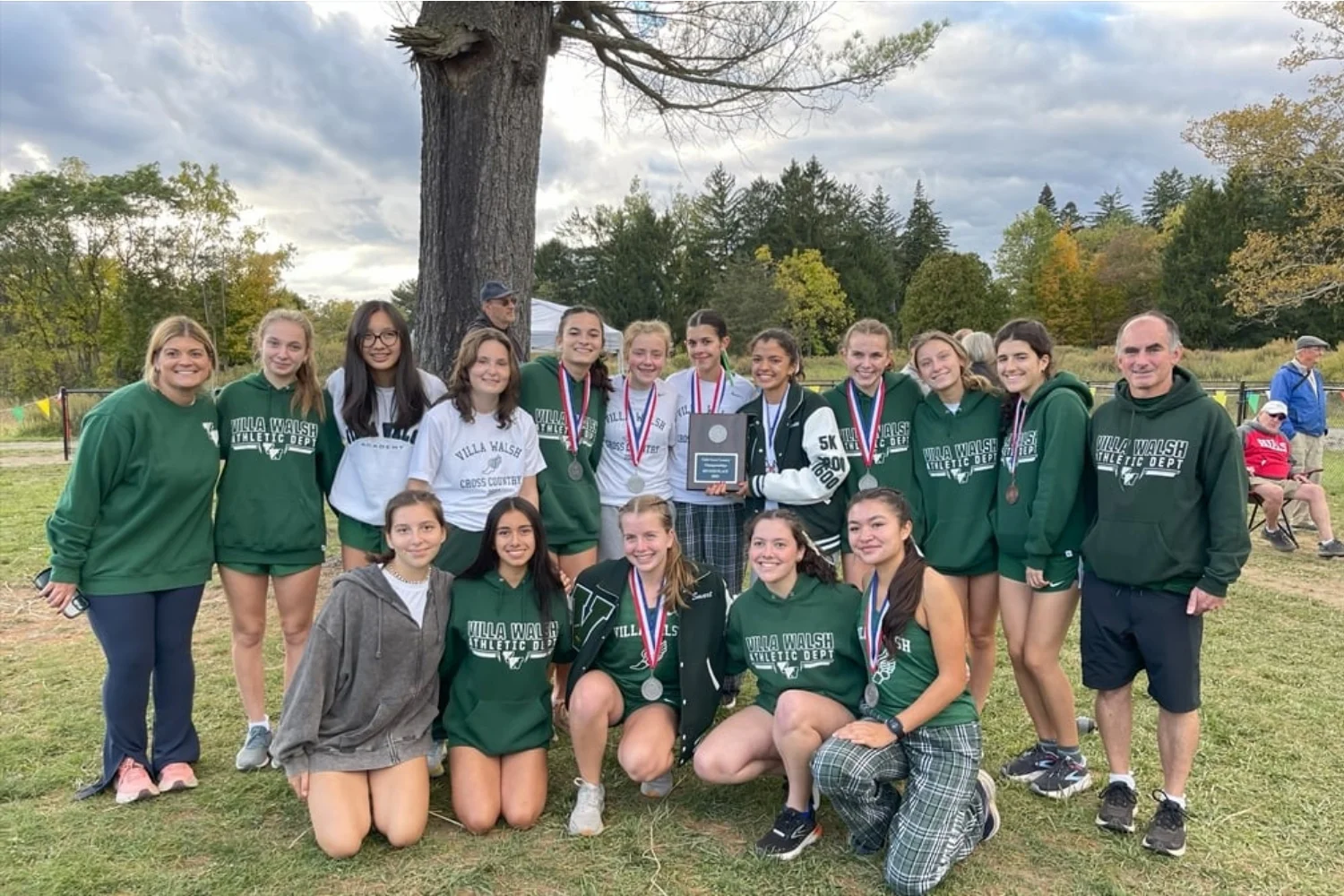 VWA cross country team wearing medals and holding award plaques