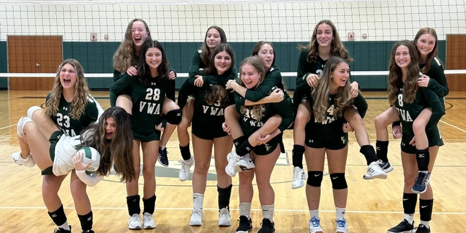 JV volleyball team posing on each others shoulders