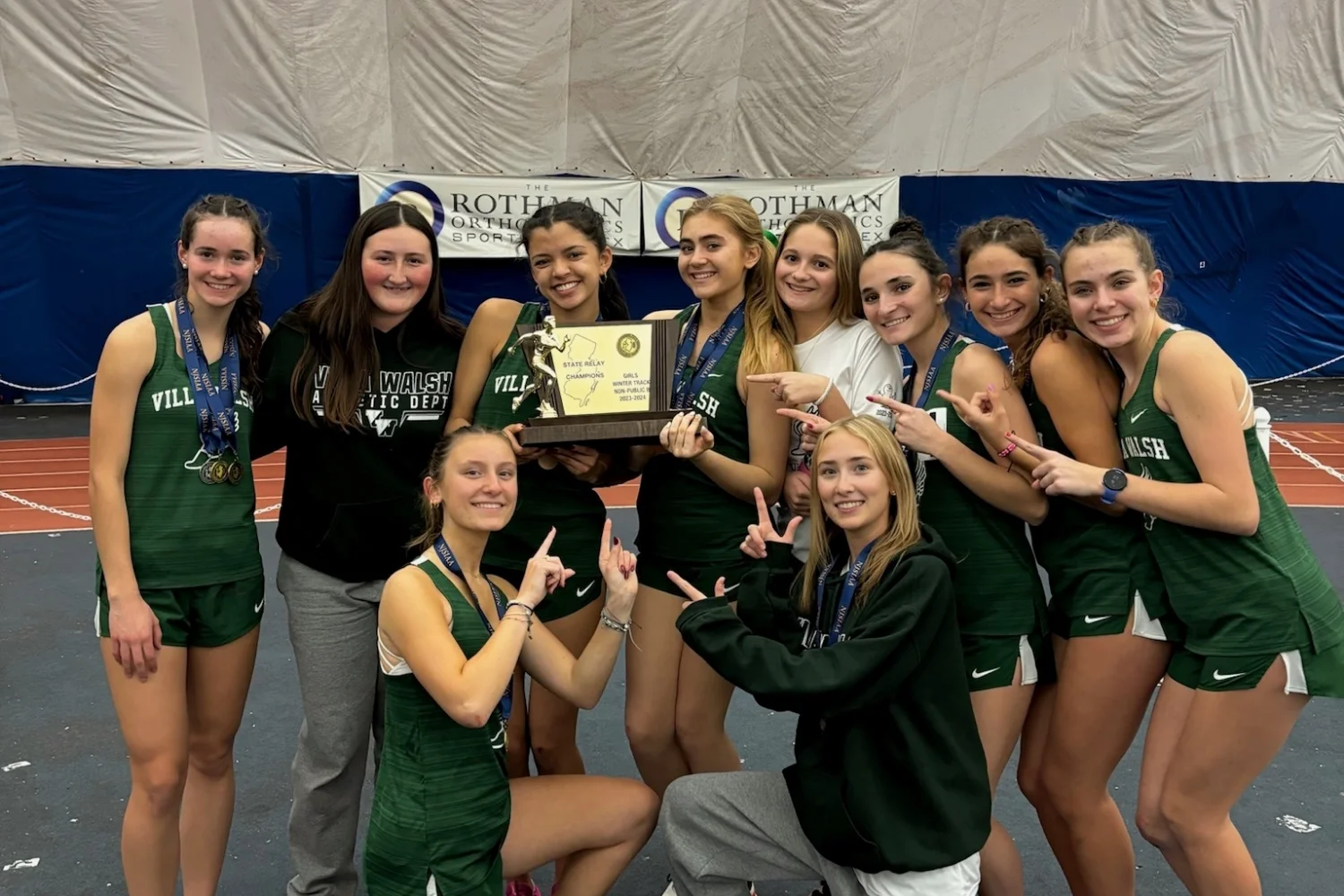 winter track team holding award plaque and wearing medals