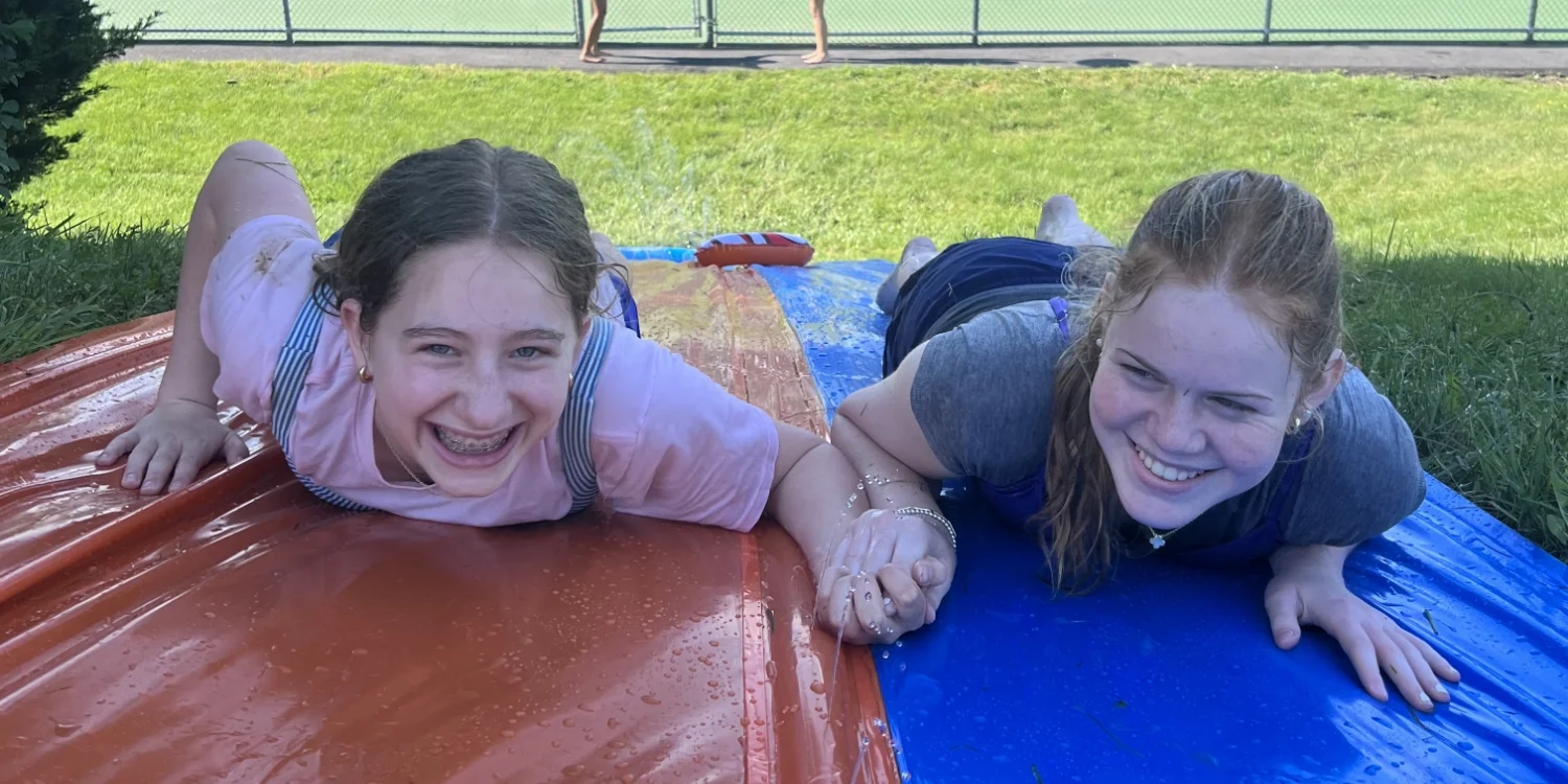 spring clinic students on water slide holding hands