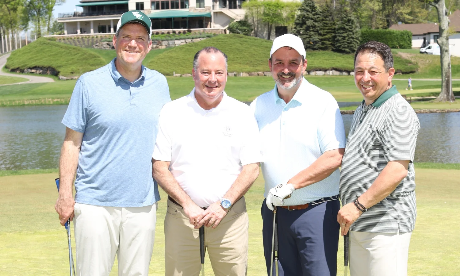 4 men in golf dress on the green