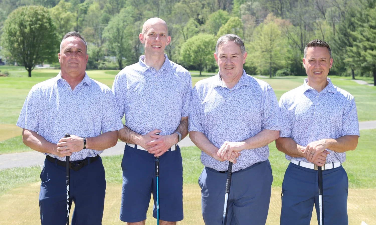 4 men in matching shirts on the green