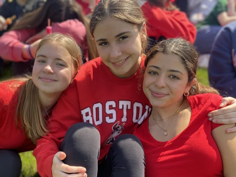 3 students sitting on the field eating popsicles